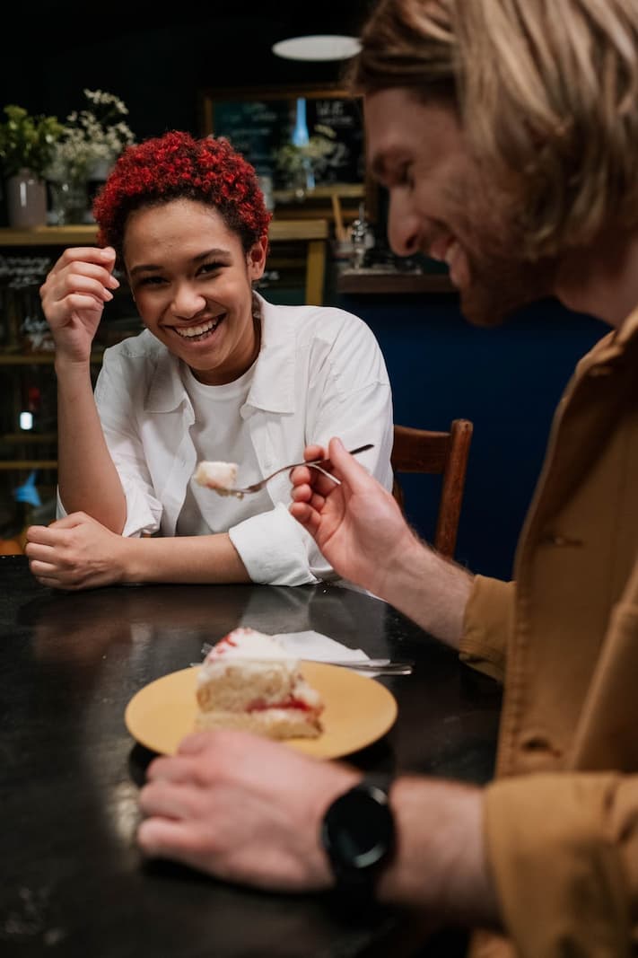 man eating cheesecake and woman laughing