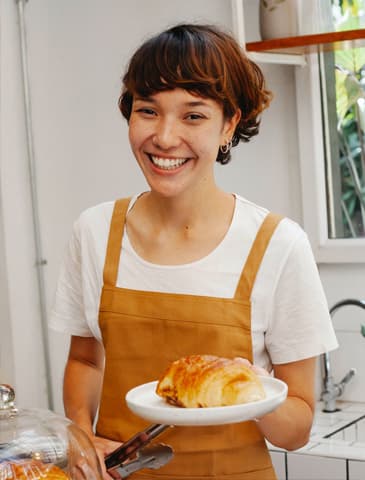 woman holding a croissant on a plate